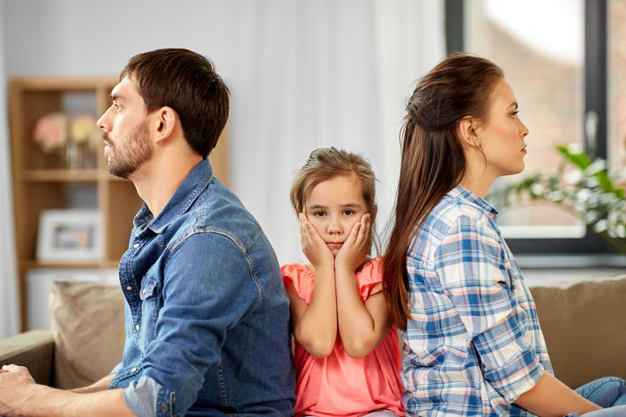 Frustrated couple sitting back to back with unhappy child between them, illustrating conflicts dating men with kids. Frustrated couple sitting back to back with unhappy child between them, illustrating conflicts dating men with kids.