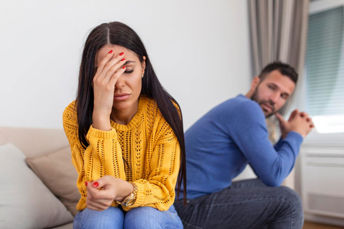 Woman in yellow sweater upset and stressed while man in blue shirt looks away, highlighting struggles dating men with kids. Woman in yellow sweater upset and stressed while man in blue shirt looks away, highlighting struggles dating men with kids.