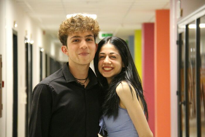 Two popular kids smiling together in a school hallway, illustrating shocking things popular kids did in school.