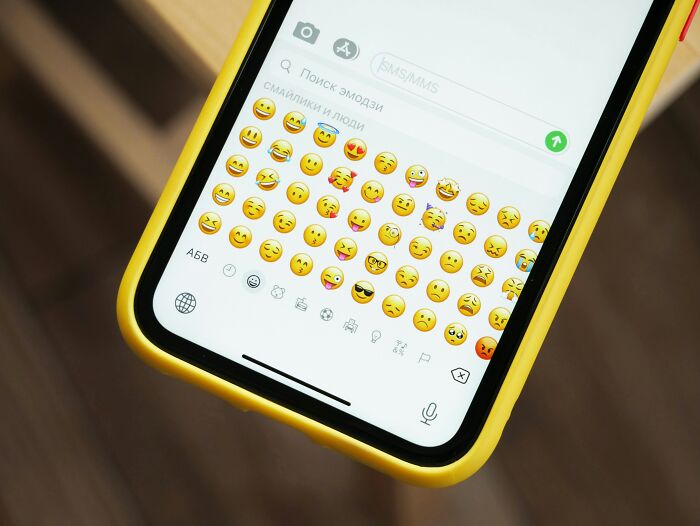 Smartphone screen showing emoji keyboard in a messaging app, illustrating parents being bad at technology skills.
