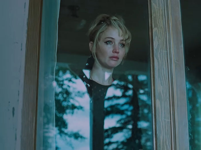 Jennifer Lawrence looking reflective and emotional, standing behind a window with trees reflected outside, related to art dealer topic. Jennifer Lawrence looking reflective and emotional, standing behind a window with trees reflected outside, related to art dealer topic.