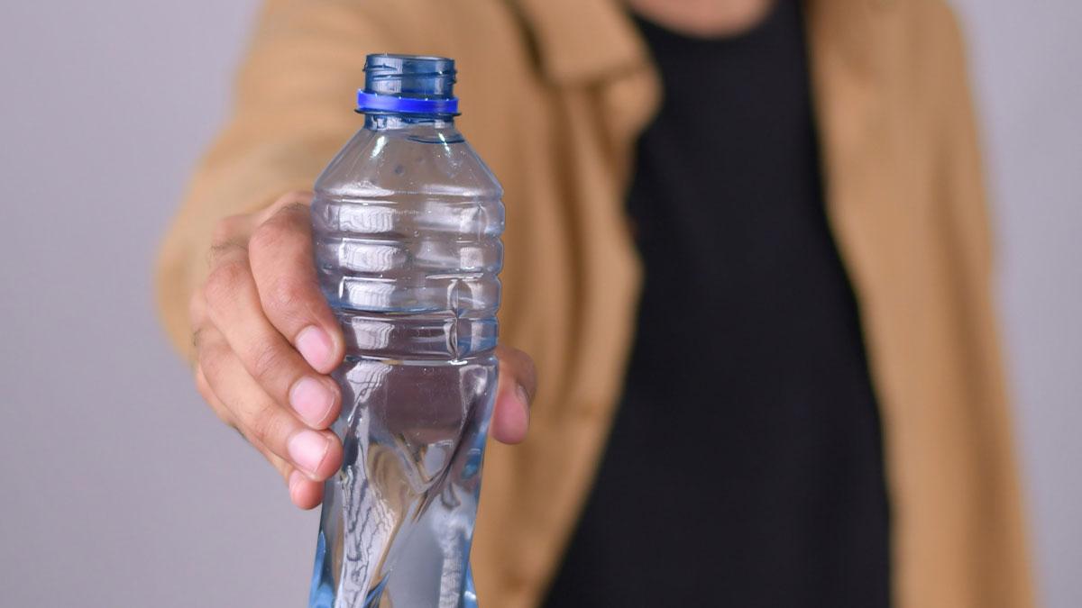 Person holding a clear plastic water bottle with focus on the bottle, related to Google diagnosing people.