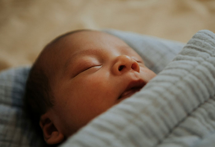 Newborn baby sleeping peacefully wrapped in a blanket, illustrating birth meltdowns witnessed by doctors during delivery.