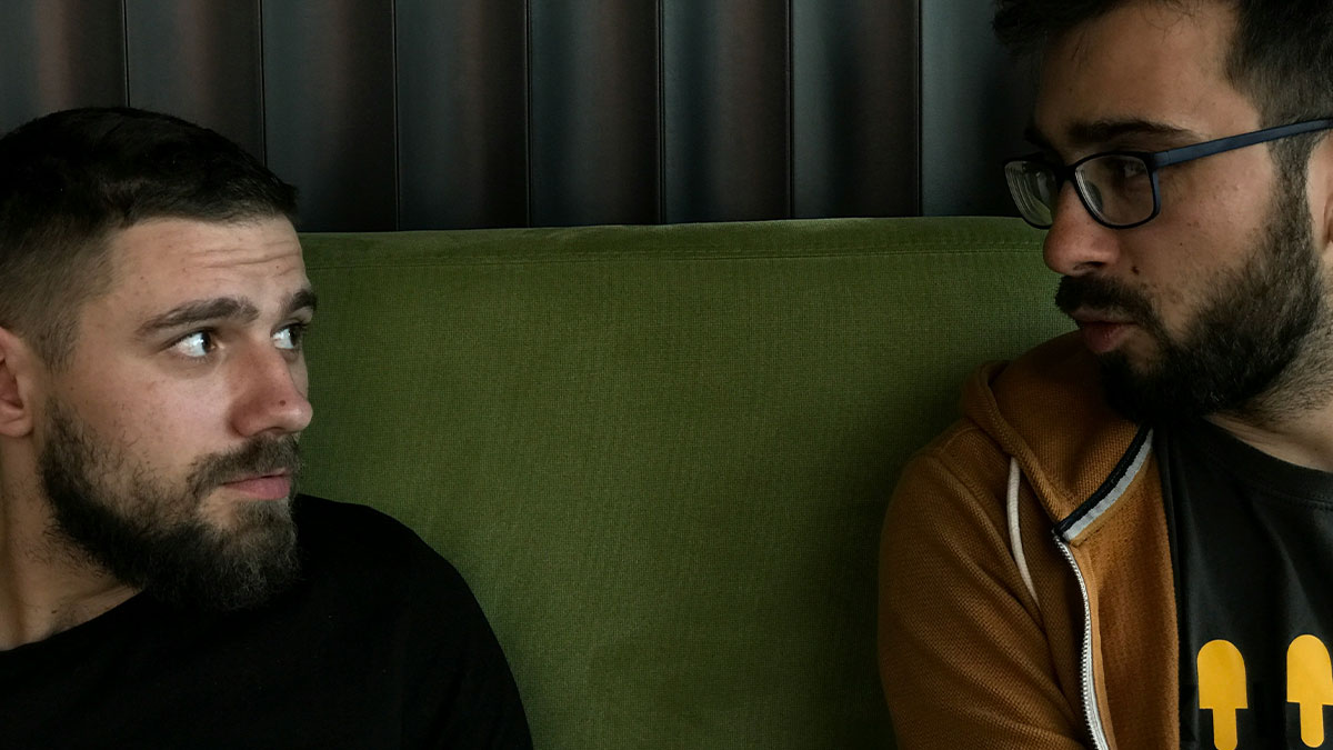 Two men with beards talking intensely on a green couch, illustrating birth meltdowns witnessed by doctors.