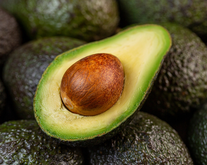 Close-up of a halved avocado with pit, highlighting the avocado hands warning and common kitchen injury risk. Close-up of a halved avocado with pit, highlighting the avocado hands warning and common kitchen injury risk.