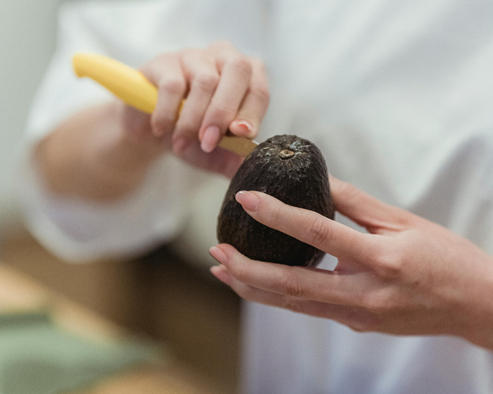 Person holding avocado and knife, demonstrating common mistake linked to doctor's avocado hands warning and ER visits. Person holding avocado and knife, demonstrating common mistake linked to doctor's avocado hands warning and ER visits.