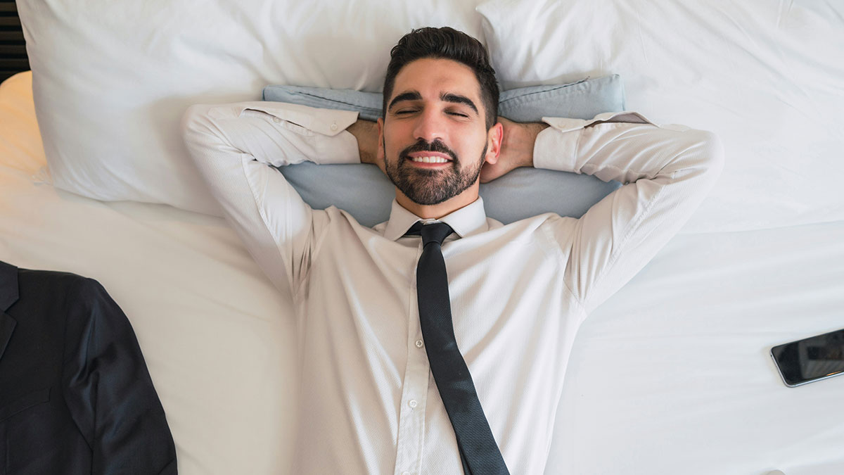 Man in white shirt and black tie lying on bed with eyes closed, reflecting on benefits for women to get married