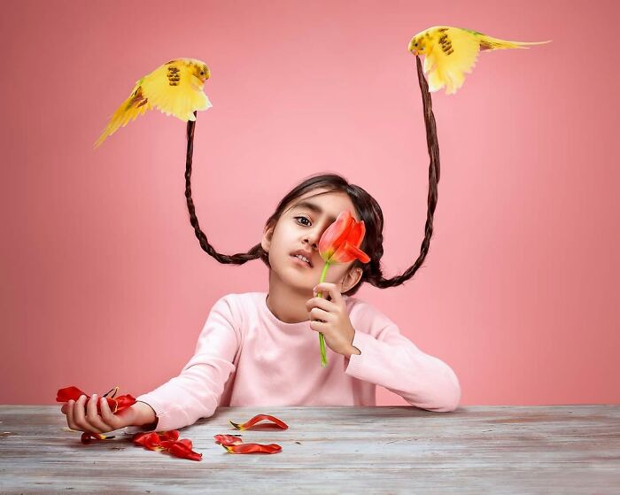 Young girl with braided hair held by yellow birds, holding a red flower, symbolizing childhood beauty and innocence.