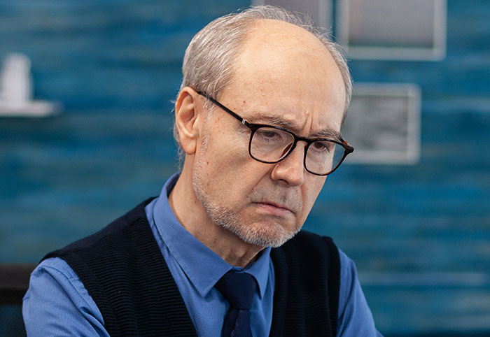 Elderly businessman with glasses in an office, looking concerned about a lost big client due to an easily replaceable employee Elderly businessman with glasses in an office, looking concerned about a lost big client due to an easily replaceable employee