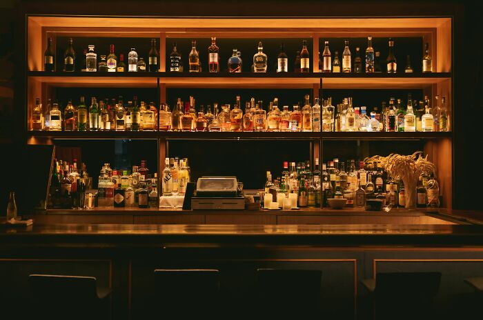 Dimly lit home bar with a variety of liquor bottles on shelves, illustrating strange and weird things workers have seen inside homes