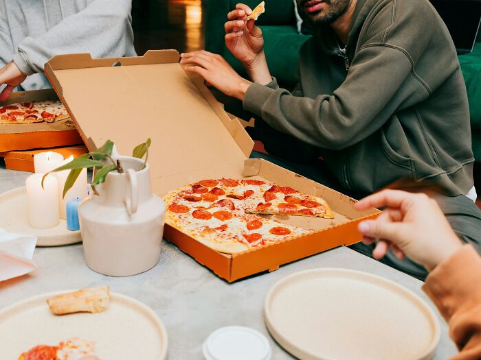 People sharing pepperoni pizza at a table, illustrating restaurant staff tales about when the bill comes and money doesn’t pay.