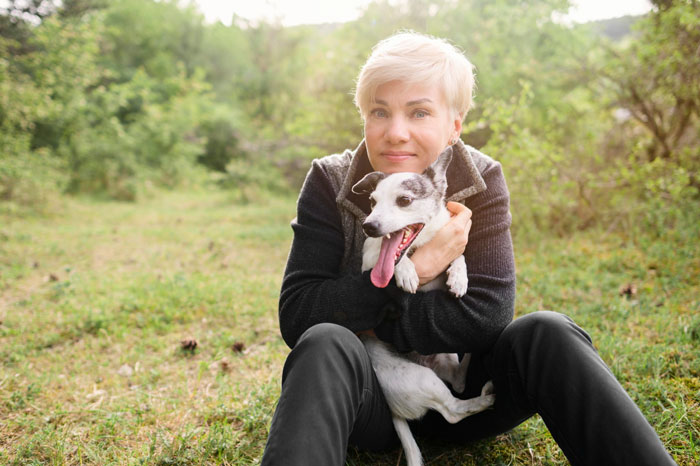 Elderly lady sitting outdoors hugging a happy dog, illustrating a story about allegedly planning to steal neighbor’s doggo. Elderly lady sitting outdoors hugging a happy dog, illustrating a story about allegedly planning to steal neighbor’s doggo.