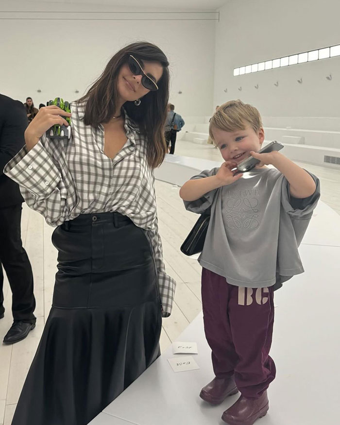 Victoria’s Secret model wearing sunglasses and a plaid shirt posing with a smiling child in a modern white space. Victoria’s Secret model wearing sunglasses and a plaid shirt posing with a smiling child in a modern white space.