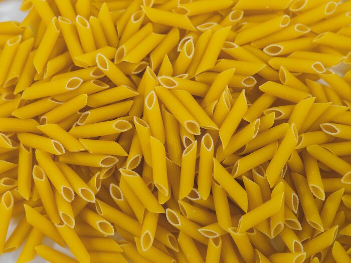 Close-up of uncooked penne pasta scattered, unrelated to shrimp jello or food served at home. Close-up of uncooked penne pasta scattered, unrelated to shrimp jello or food served at home.