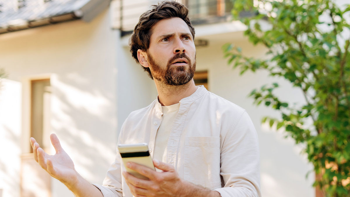 Man with phone outside home looking confused and frustrated dealing with neighbors in Karen mode conflict.