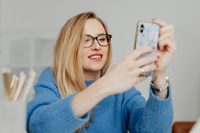 Young woman in glasses smiling while taking a selfie, illustrating wife cheats and starts a new life with lover concept. Young woman in glasses smiling while taking a selfie, illustrating wife cheats and starts a new life with lover concept.
