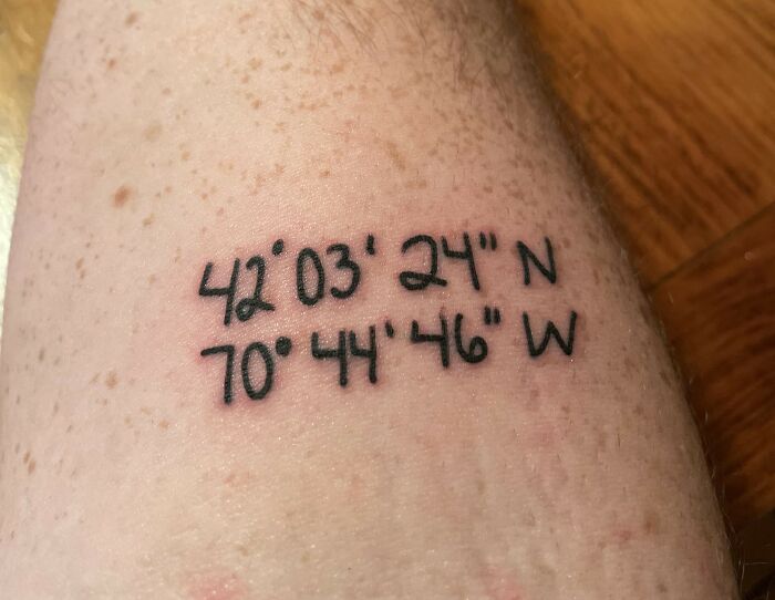 Tattoo of geographic coordinates on light-toned skin, showcasing unique ink from unusual tattoo artists.