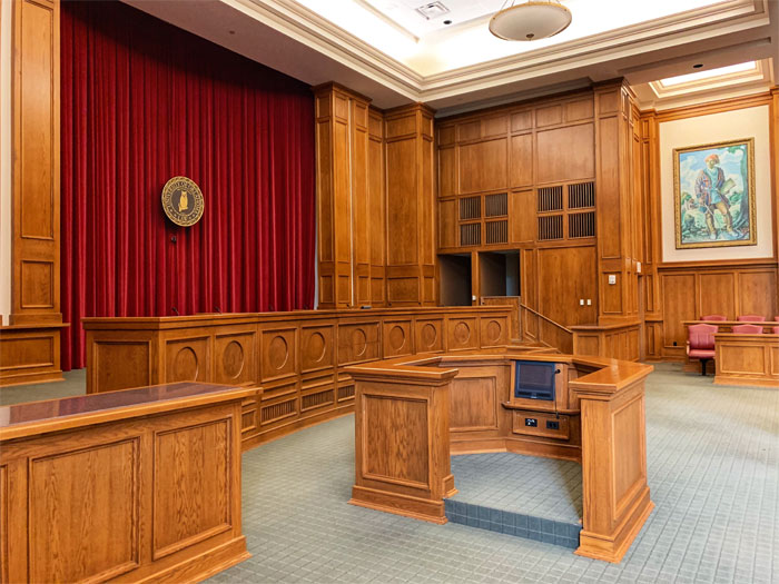 Courtroom interior with wooden paneling and red curtains representing a family heirloom legal dispute case setting. Courtroom interior with wooden paneling and red curtains representing a family heirloom legal dispute case setting.