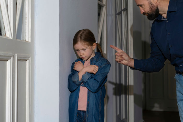 Young daughter looking upset while being scolded, highlighting family scapegoat and regret themes. Young daughter looking upset while being scolded, highlighting family scapegoat and regret themes.