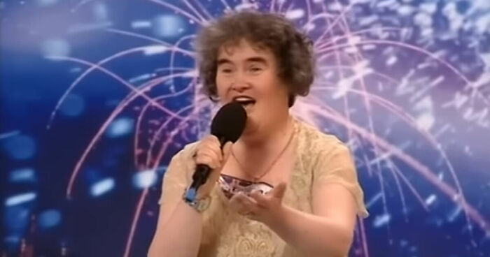 Susan Boyle singing on stage during a Britainu2019s Got Talent performance with colorful fireworks in the background.