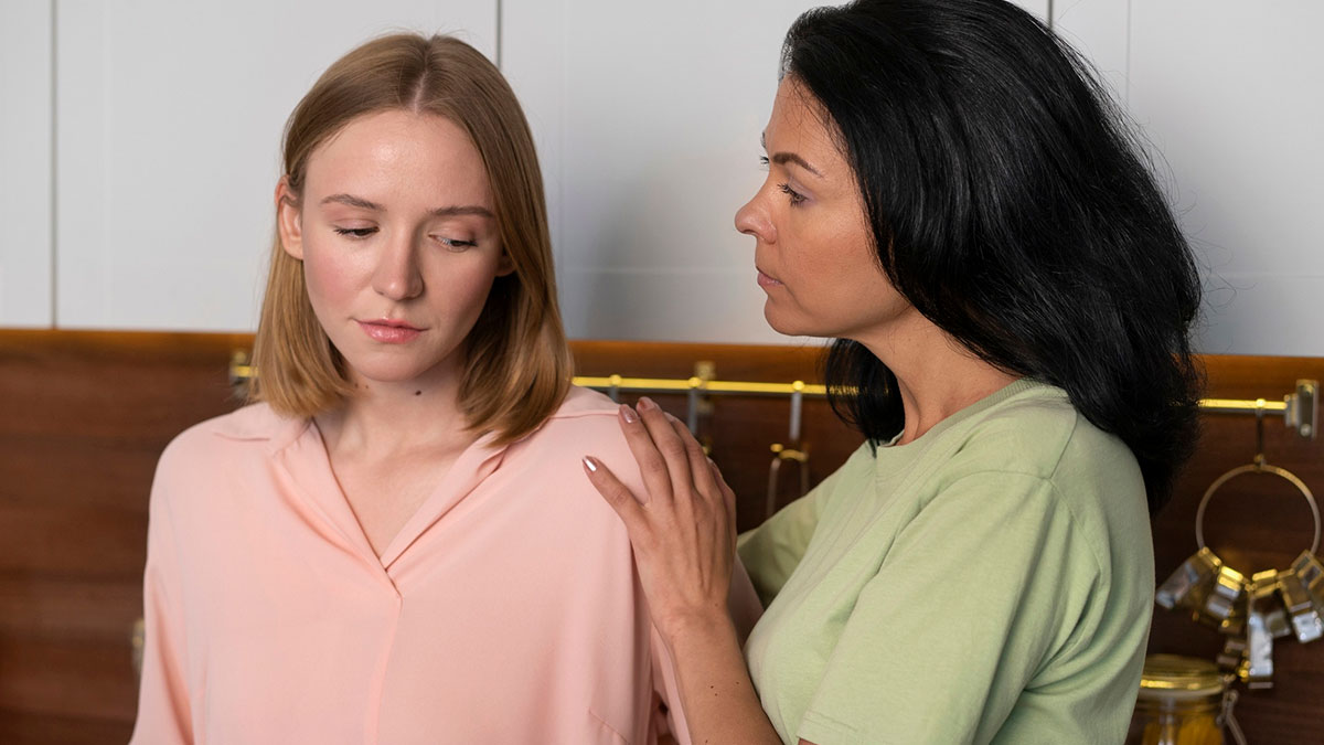 Woman feeling sorry for friends daughter, comforting her with a hand on the shoulder in a home setting