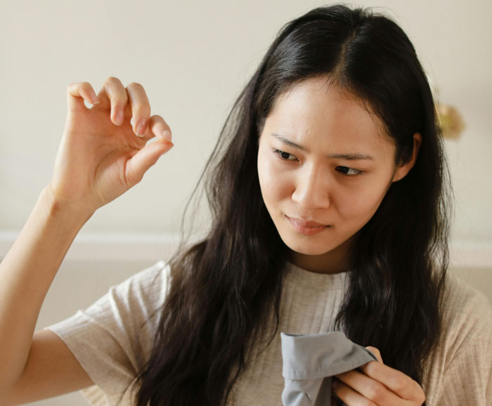 Woman holding a strand of hair while cleaning the house, discovering evidence of a serial cheater caught red-handed. Woman holding a strand of hair while cleaning the house, discovering evidence of a serial cheater caught red-handed.