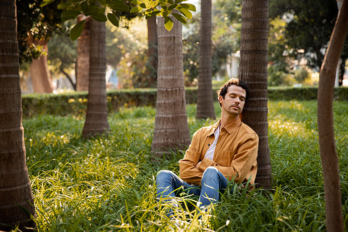 Man sitting alone in a park looking uneasy, reflecting the creepy feeling of finding secret photos taken without consent. Man sitting alone in a park looking uneasy, reflecting the creepy feeling of finding secret photos taken without consent.