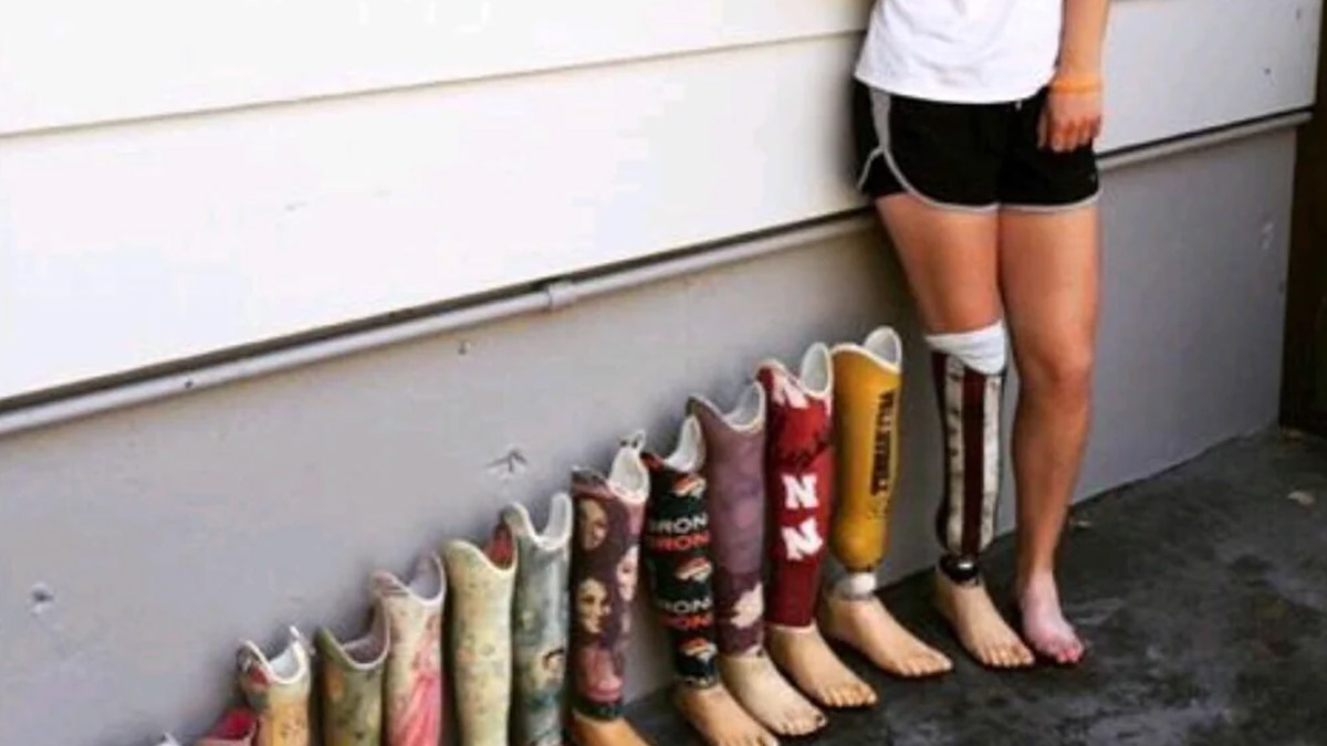 Person standing with a prosthetic leg among a row of colorful prosthetic legs against a wall dating apps humor