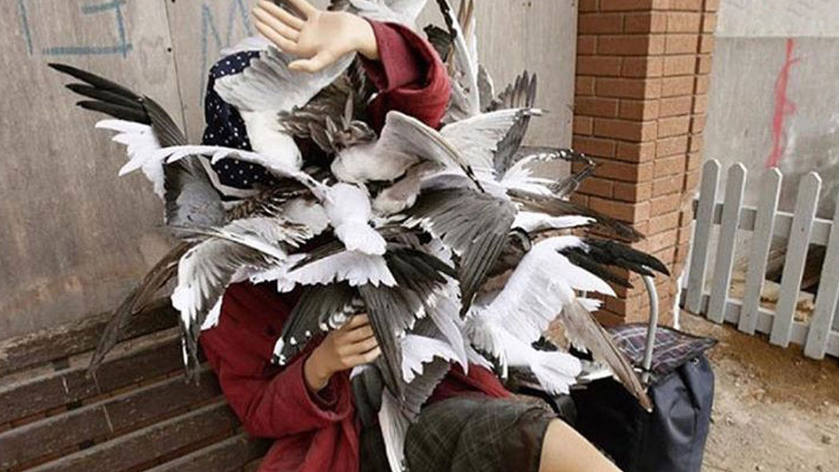 Person in red jacket shielding from a large flock of birds, illustrating relatable chaos in parenting memes.