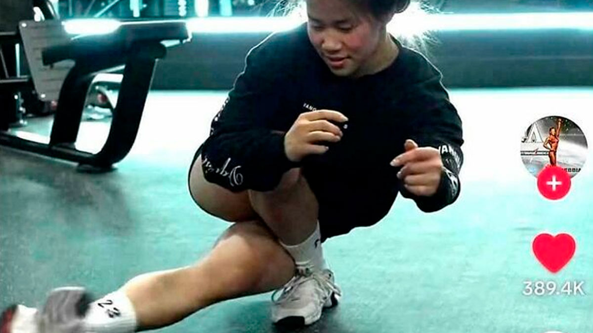 Young woman smiling while stretching on the floor in a gym, showing the fun side of comments better than the post.