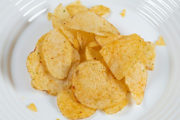 Close-up of seasoned potato chips served on a white plate, illustrating a snack option unlike shrimp jello.
