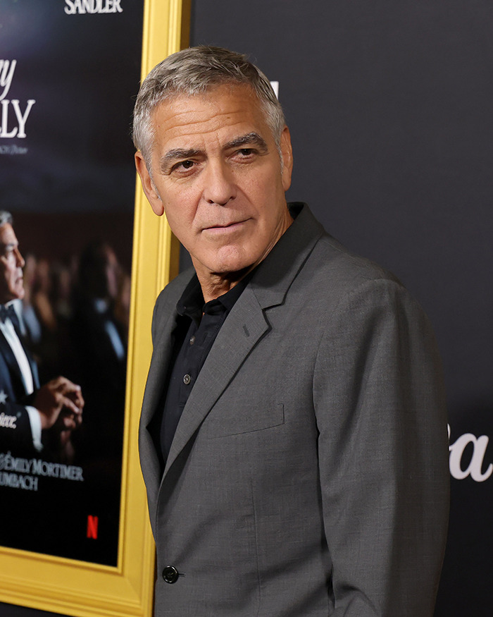George Clooney in a gray suit at a film premiere, addressing allegations related to Virginia Giuffre's Epstein memoir.
