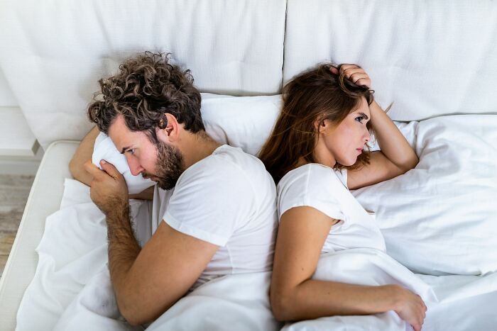 Couple lying in bed back to back looking upset, illustrating relationship advice for improving couple communication.