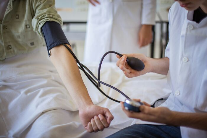 Healthcare worker measuring a patient's blood pressure inside a stranger's home, highlighting weird things workers have seen.