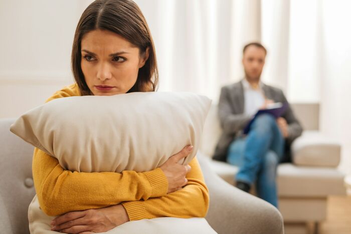 Woman looking upset hugging a pillow during a counseling session focused on relationship advice for couples.