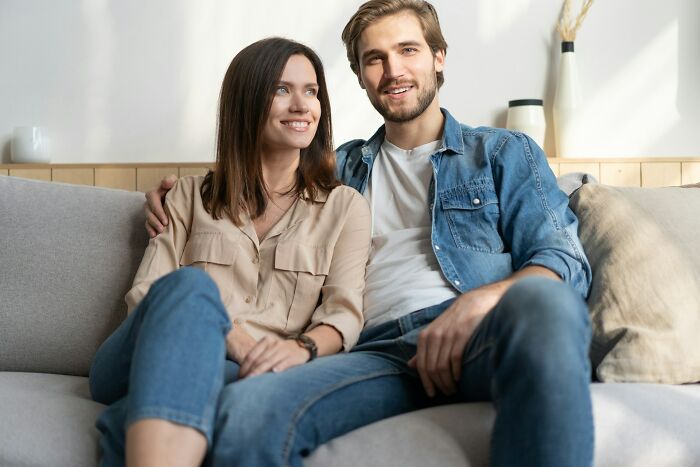 Happy couple sitting closely on couch, enjoying relationship advice and bonding in a relaxed home setting.