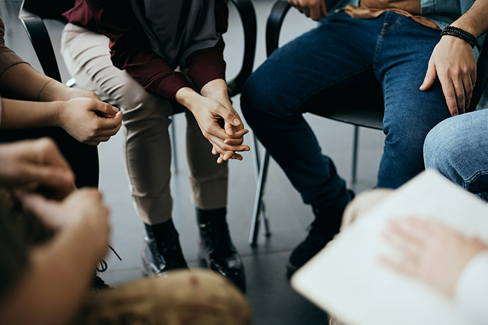 Group therapy session with people sitting in a circle discussing sensitive topics related to IVF and family dynamics. Group therapy session with people sitting in a circle discussing sensitive topics related to IVF and family dynamics.