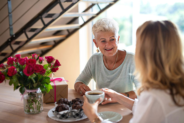 Elderly grandma smiling at woman during coffee, highlighting family care and refusal to take responsibility challenges. Elderly grandma smiling at woman during coffee, highlighting family care and refusal to take responsibility challenges.