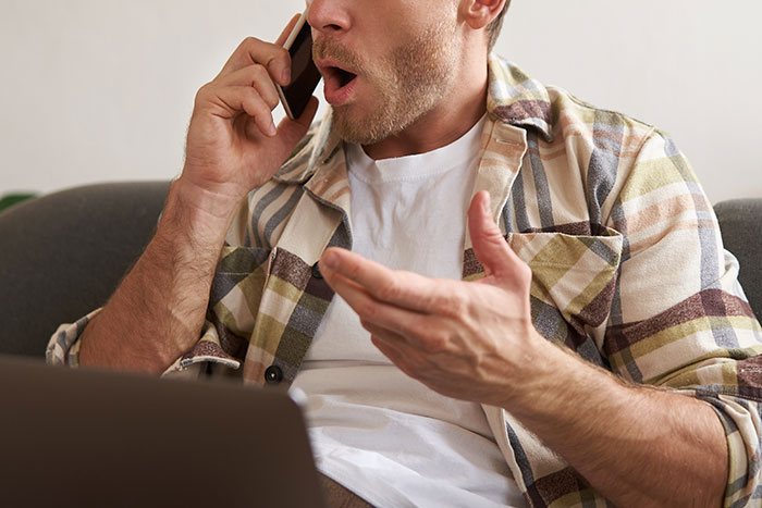 Man in a plaid shirt speaking on phone with a frustrated expression, illustrating depressed is not an excuse for being lazy. Man in a plaid shirt speaking on phone with a frustrated expression, illustrating depressed is not an excuse for being lazy.