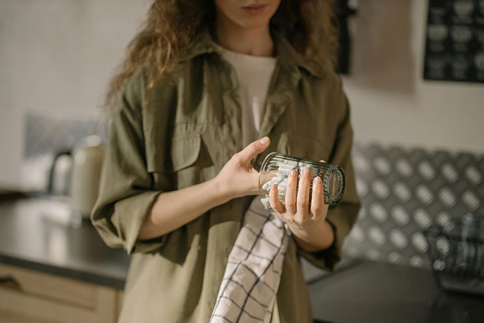 Woman in casual clothes holding a glass and towel, reflecting on emotions related to depressed and lazy behavior. Woman in casual clothes holding a glass and towel, reflecting on emotions related to depressed and lazy behavior.
