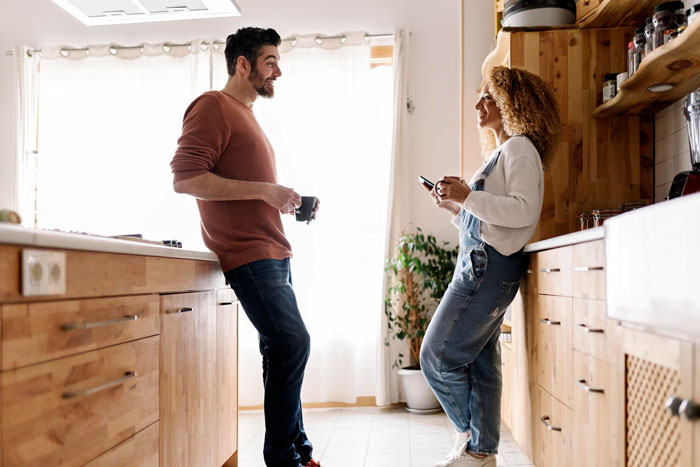 Man and woman in kitchen having a tense conversation, related to man kicking out girlfriend after secret invite of ex. Man and woman in kitchen having a tense conversation, related to man kicking out girlfriend after secret invite of ex.