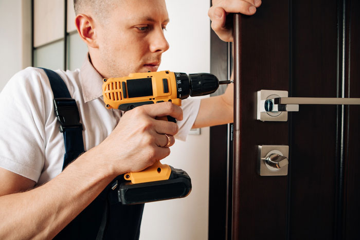 Man using power drill to secure door lock, symbolizing man kicking out girlfriend and her 9-year-old son from house. Man using power drill to secure door lock, symbolizing man kicking out girlfriend and her 9-year-old son from house.