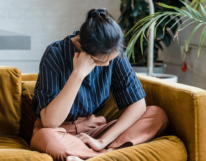 Woman sitting on couch looking upset, reflecting on boyfriend going on trip with female friend and relationship concerns. Woman sitting on couch looking upset, reflecting on boyfriend going on trip with female friend and relationship concerns.
