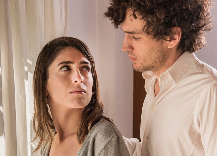 Couple having a tense conversation indoors, woman looking upset while man seems to be reconsidering their relationship. Couple having a tense conversation indoors, woman looking upset while man seems to be reconsidering their relationship.