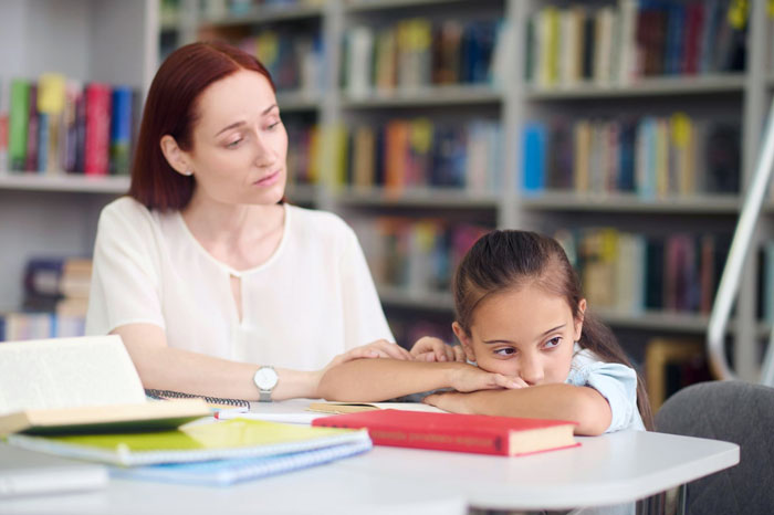 Teacher comforting upset child in classroom setting after hermit crab pet issue, highlighting pet care concerns and parental backlash. Teacher comforting upset child in classroom setting after hermit crab pet issue, highlighting pet care concerns and parental backlash.
