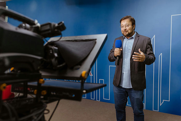 Reporter sharing moments with famous family members, holding a microphone during a video shoot in a studio setting.