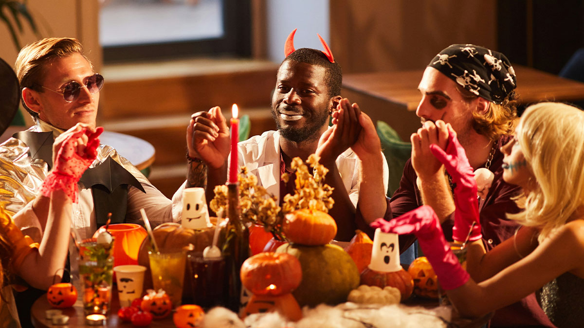 Group of friends in Halloween costumes around a decorated table at a Halloween wedding celebration.