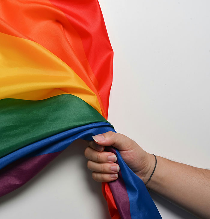 Hand gripping a vibrant pride flag, symbolizing the Florida man incident involving a Starbucks tantrum over the flag.