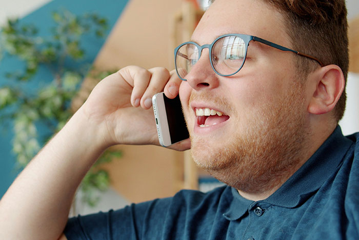 Man with glasses talking on smartphone indoors, representing hard truths women realize and accept in their lives.