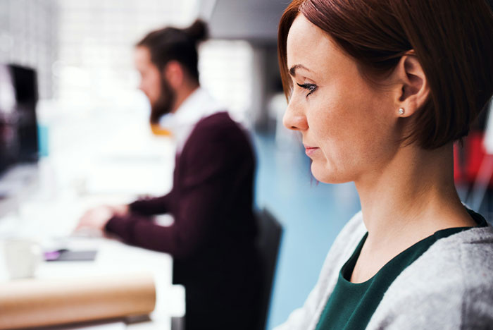 Woman reflecting thoughtfully in an office setting, representing hard truths women realize and accept in life.